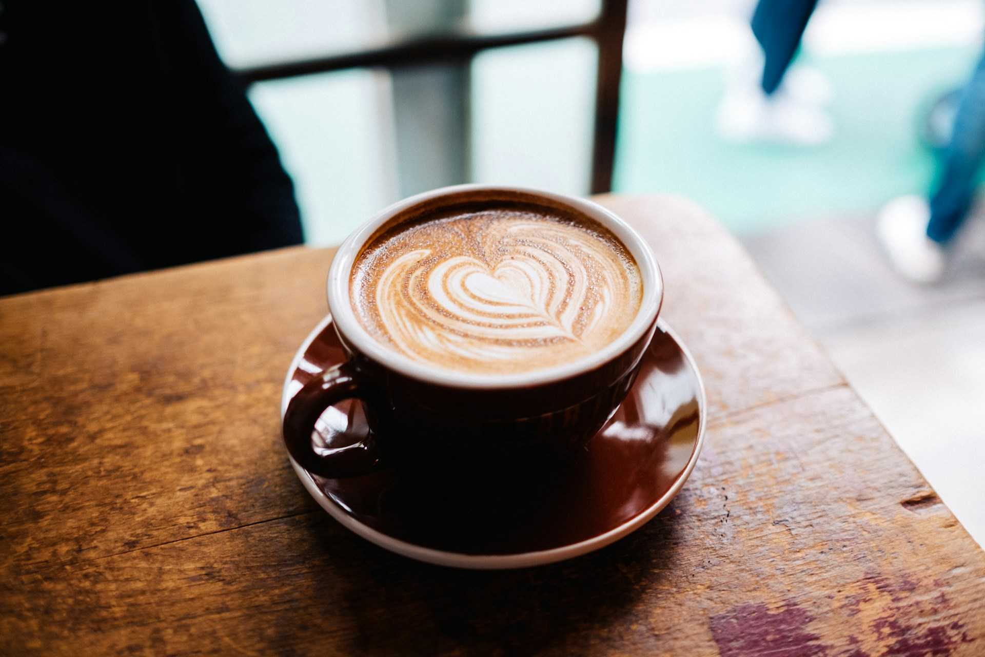 Tasse de café sur une table en bois avec un motif en forme de cœur dans la crème